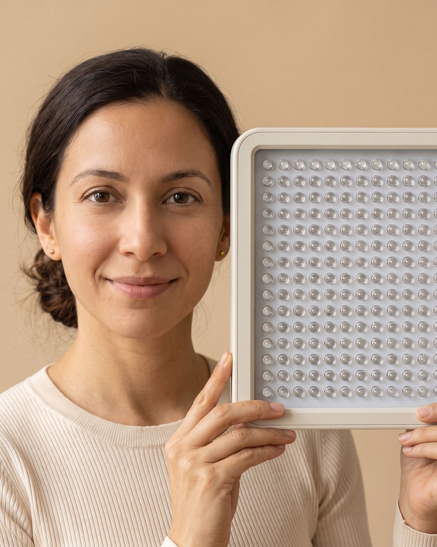 Woman holding the Folliq Portable Face Panel beside her face to show its size, LEDs off