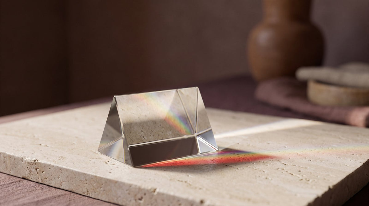 Glass prism on a stone surface splitting light into a spectrum of colors