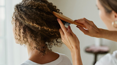A mother gently brushing her healthy hair in soft morning light
