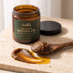 Texture of Folliq unrefined batana paste melting into oil on a wooden spoon