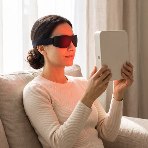 Woman in protective goggles holding the Folliq Portable Face Panel, red channel on, about 15 cm from her face