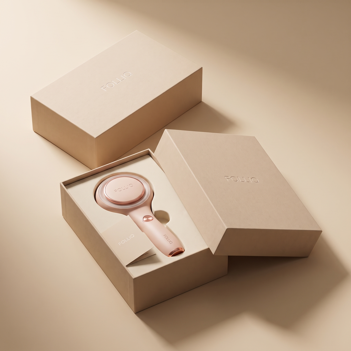 The Folliq massager resting in its open kraft gift box, the lid set beside it