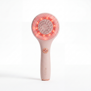 The Folliq Red Light Scalp Massager in blush pink, standing upright with its red LED ring lit
