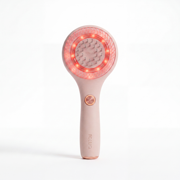 The Folliq Red Light Scalp Massager in blush pink, standing upright with its red LED ring lit