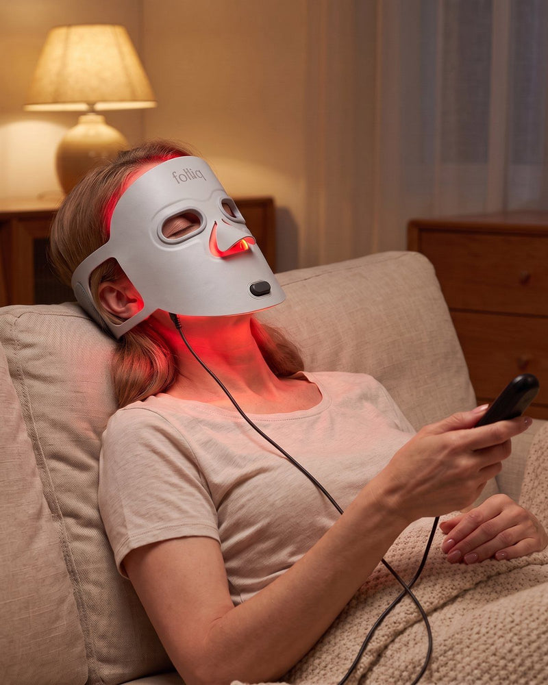 Woman resting on a sofa during a ten-minute Folliq LED face mask session