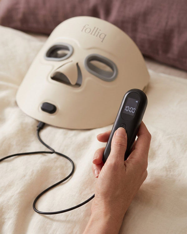 Folliq face mask controller in a hand, showing the 10-minute timer