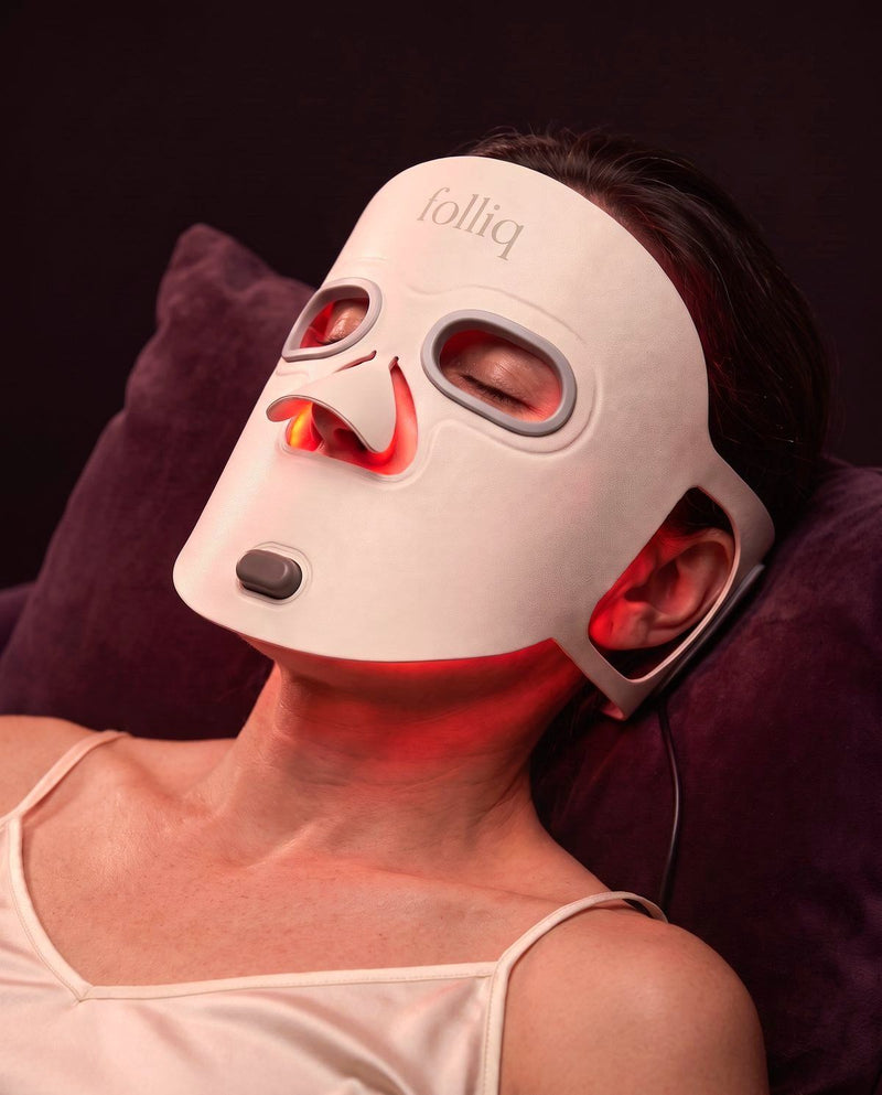 Woman resting with the Folliq Red Light Therapy Face Mask switched on